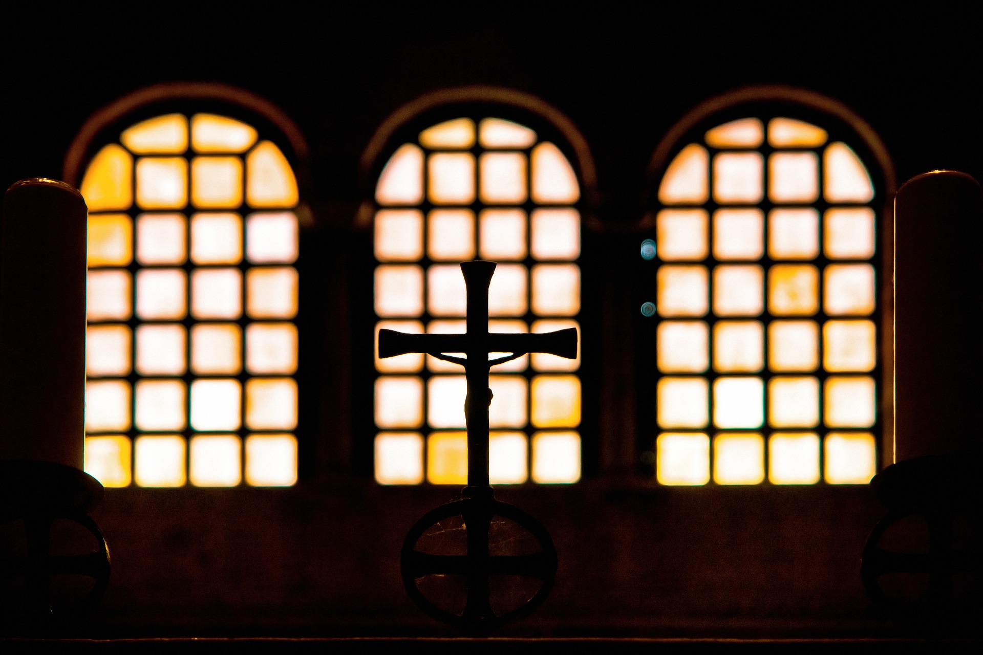 A silhouette shot of the Cross in front of antique wooden windows