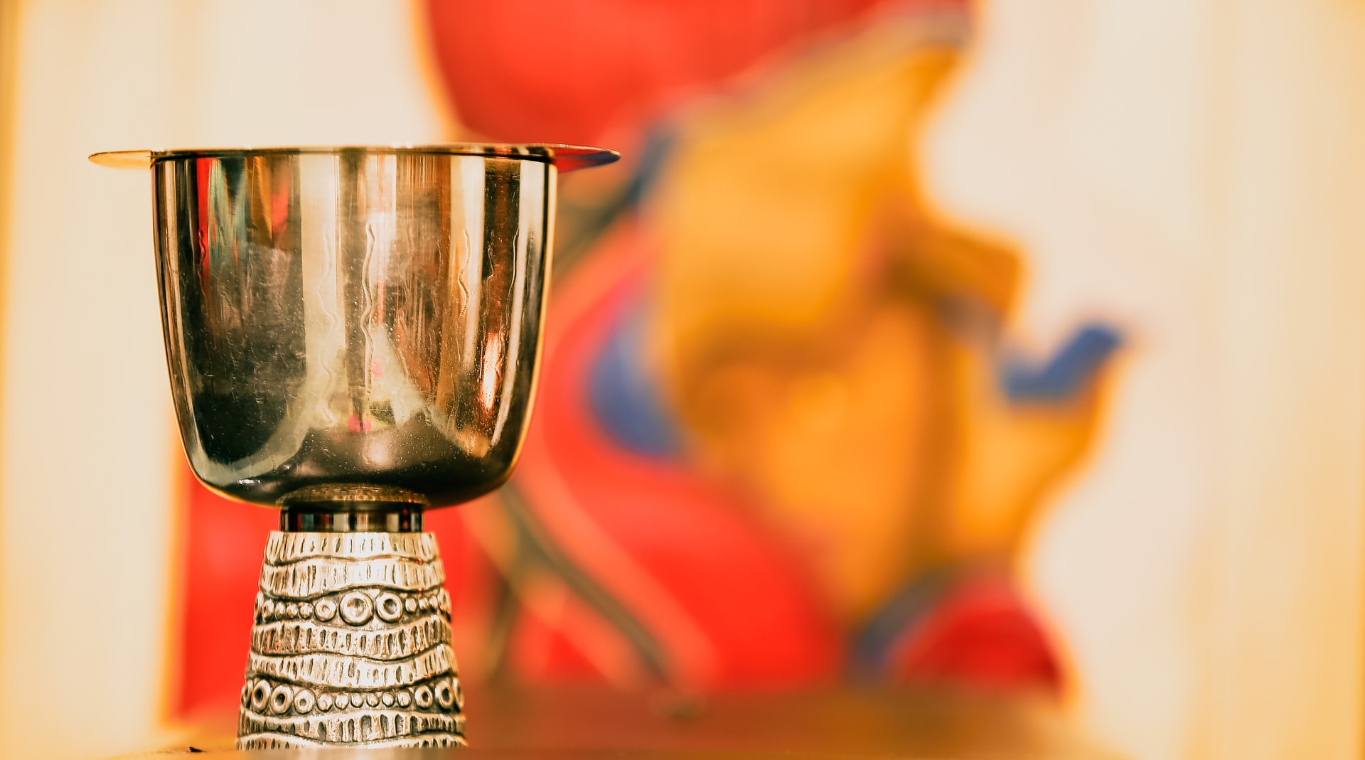 A chalice in front of an out-of-focus painting of the Blessed Virgin Mary