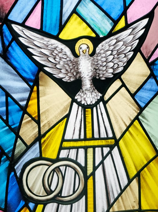 A stained glass window depicting the Holy Spirit and two rings symbolizing marriage