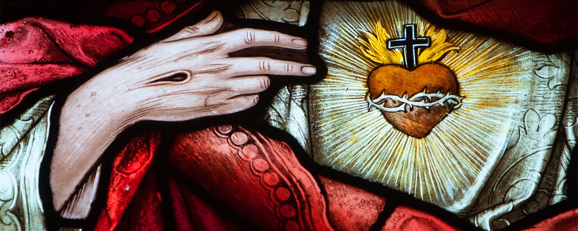A stained glass image of Jesus pointing to His Sacred Heart