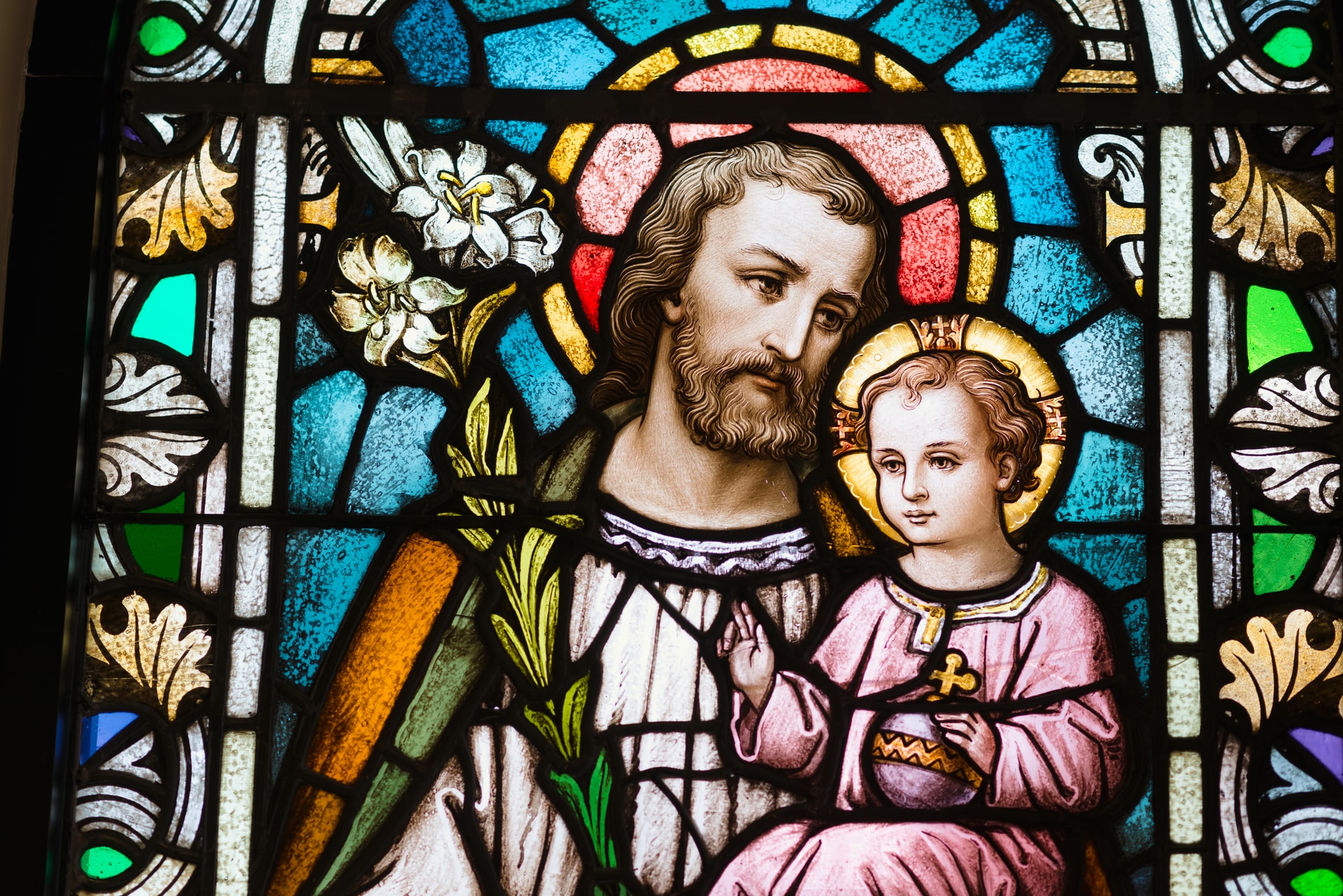 A stained glass window depicting St. Joseph carrying the child Jesus
